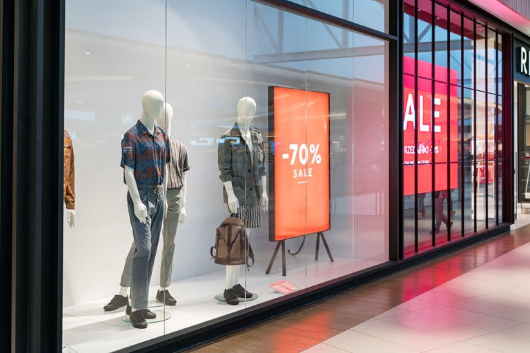 Escaparate de una tienda de ropa en donde se percibe un display publicitario encargado de mostrar las promociones existentes de esa tienda.