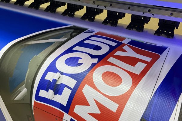 Impresión de lona con diseño de auto LIQUI MOLY utilizando tinta UV sobre material texturizado.